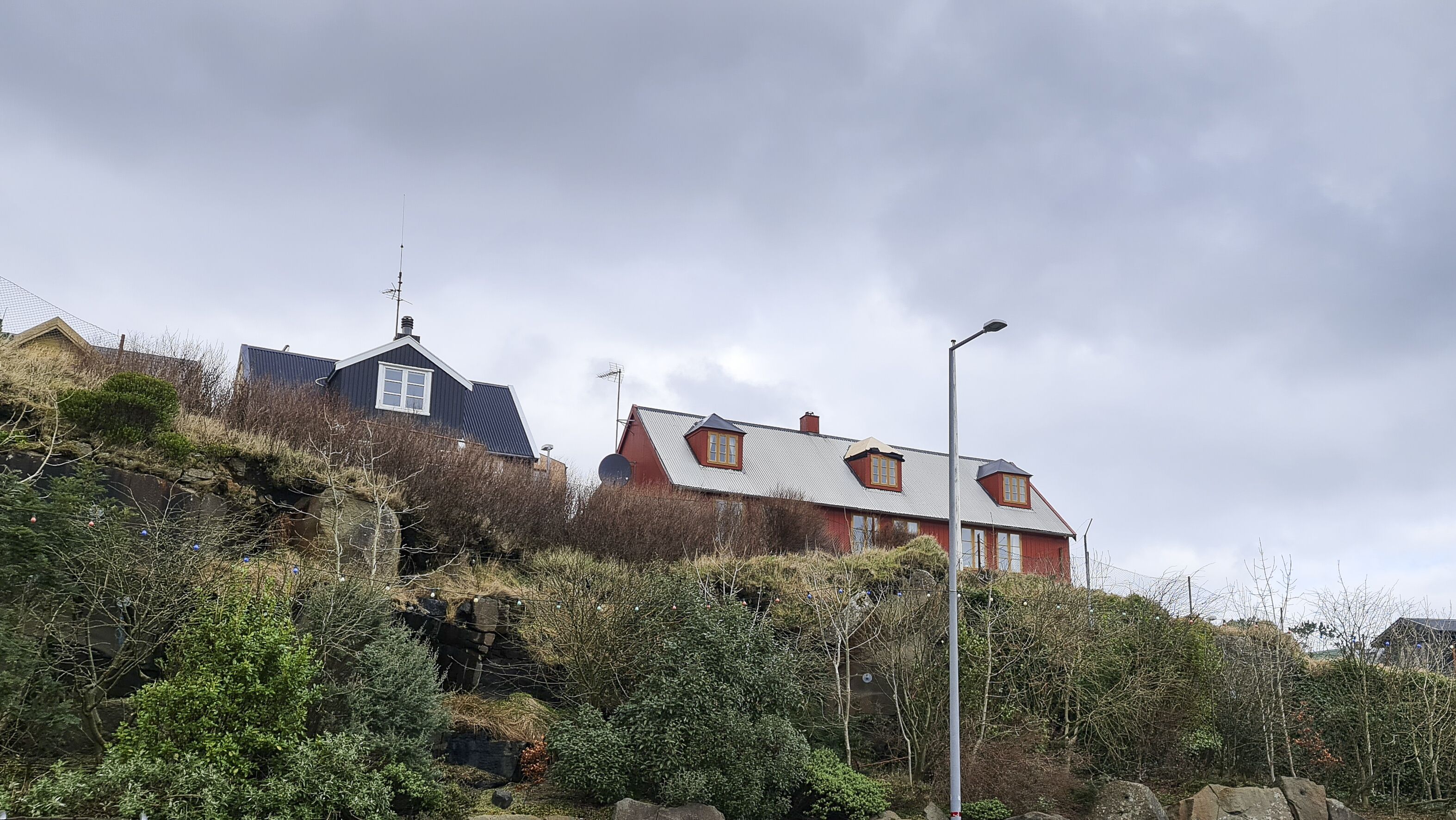 A house with a sloped roof, a satellite dish, and a street lamp.