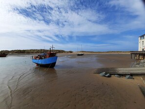 A beach with two boats, a building with a balcony, and a sandy shore. - 4A Victoria Place (Barmouth)