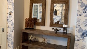 A wooden console table with two mirrors, a decorative metal piece, and candles. - Beautiful S. Main St. Historic Row House (Geneva)