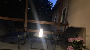Eine Terrasse mit Metallstühlen, einem Tisch, einem Blumentopf und einer Laterne.