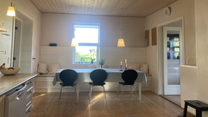 Eine moderne Küche mit Holzbalkendecke, einer Essecke mit drei Stühlen und einem Fenster, das für natürliches Licht sorgt.