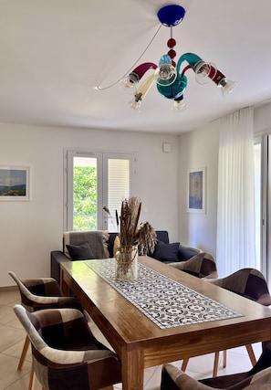 Un comedor con mesa de madera, sillas acolchadas, un florero decorativo y una lámpara colgante original.
