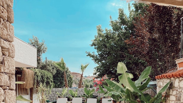 A swimming pool with lounge chairs, surrounded by stone walls and tropical plants. - Dud Otel Alaçatı (Cesme)