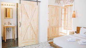 A bedroom with a bed, a wooden wardrobe, a bathroom with a sink, and a mirror. - Dud Otel Alaçatı (Cesme)