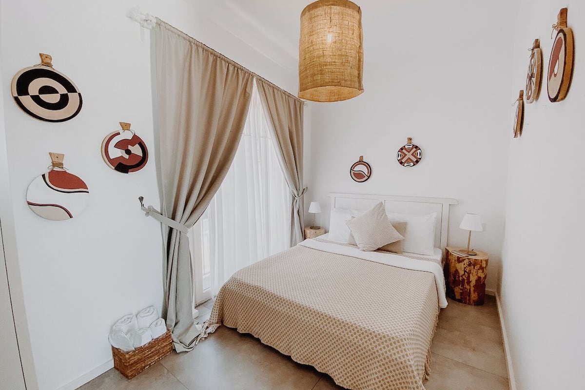 Une chambre à coucher avec un lit, une lampe suspendue et des éléments décoratifs sur les murs.