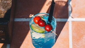 A glass with a drink, cherries, and a straw on a tiled surface. - Dud Otel Alaçatı (Cesme)