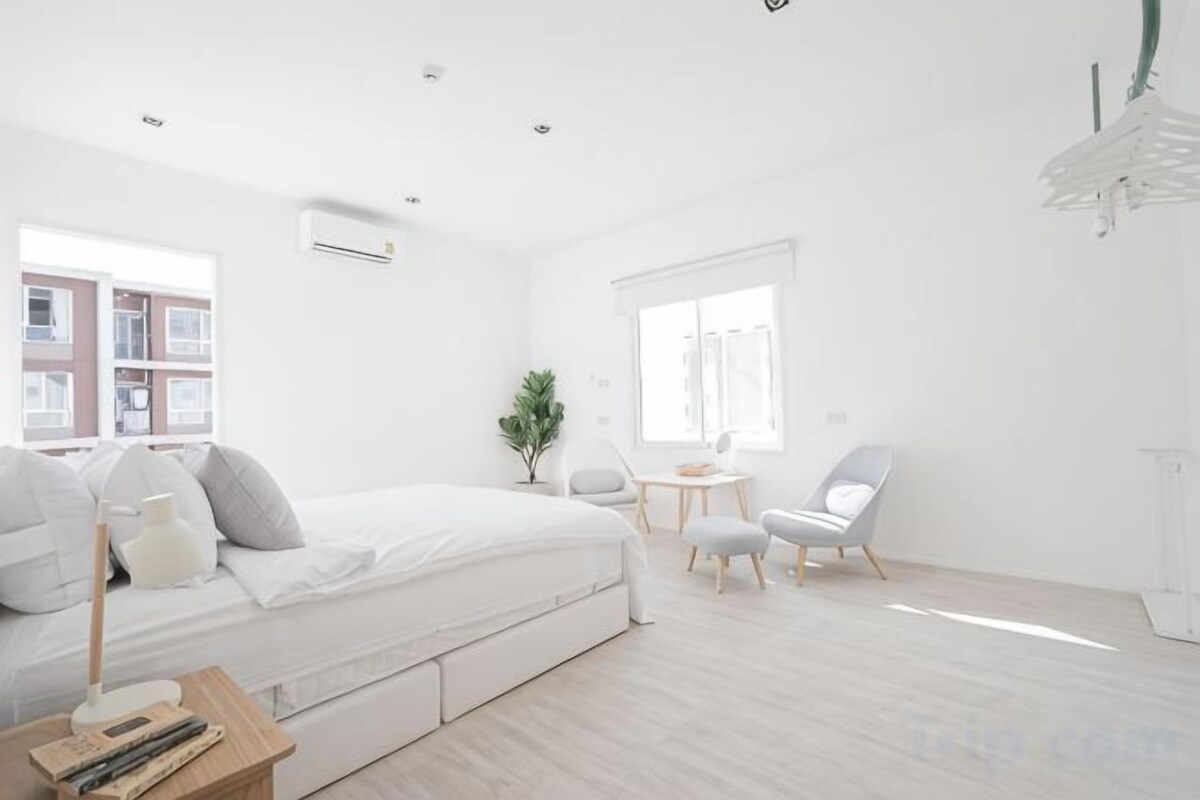 A modern bedroom with a bed, bedside table, and a small desk with a chair.