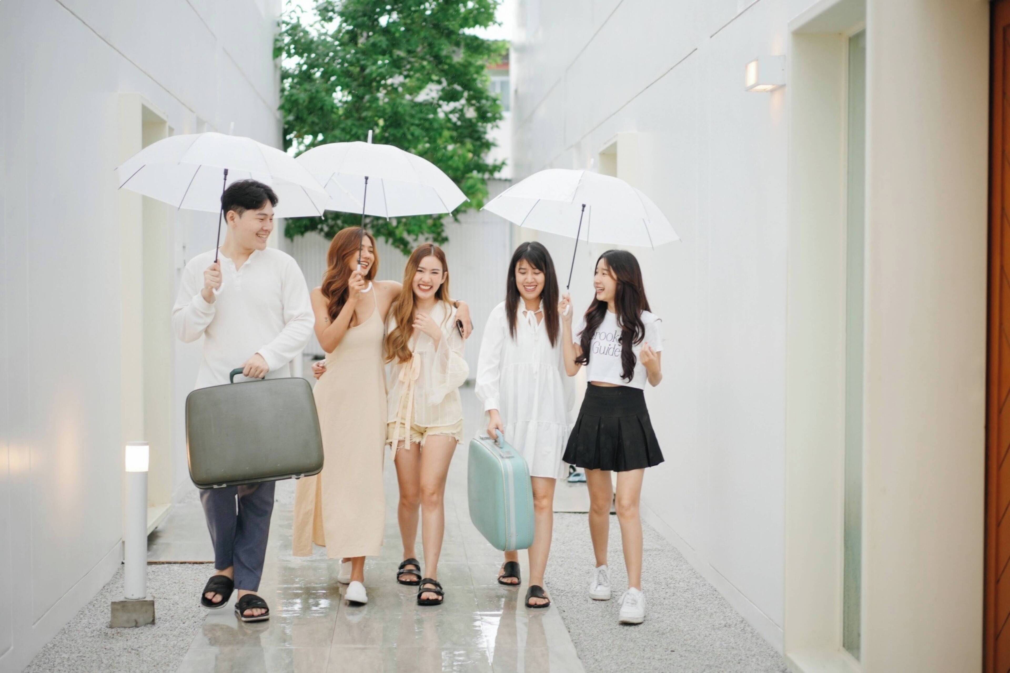 A group of people walking down a corridor with white walls and a wooden door on the right.