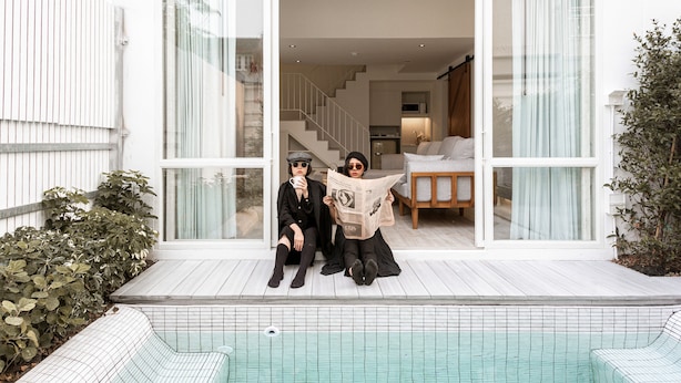 Una casa moderna con un amplio ventanal, una piscina y una escalera que conduce al interior.