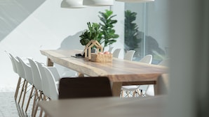 Un comedor moderno con una mesa de madera, sillas blancas y lámparas colgantes.