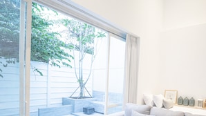 Una sala de estar moderna con un ventanal grande, un sofá gris, una mesa de centro de madera y un pequeño área de piscina.
