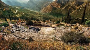 Ein uraltes Amphitheater, umgeben von Bergen und Vegetation.