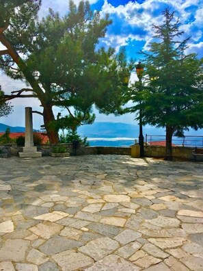 A stone-paved area with a view of the sea and mountains in the background. - DelphiCENTER-penthouse-celebrity V.I.P (Delphi)