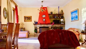 Ein Wohnzimmer mit Kamin, einer Couch, einem Esstisch und Stühlen.