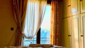 Ein Schlafzimmer mit einem Bett, einer Klimaanlage, einem Fenster mit Vorhängen und Blick ins Freie.