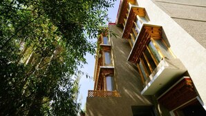 A multi-story building with wooden balconies and a view of dense foliage. - The Shanti Nest At Boutique Hotel (Leh)