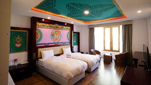 A hotel room with a large bed, two side tables, a TV, and a window with curtains. - The Shanti Nest At Boutique Hotel (Leh)