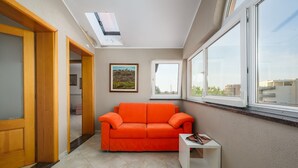 A room with a skylight, a red sofa, a small table, and a framed picture on the wall. - A one bedroom apartment with balcony and private parking in town - Dragica 2 (Umag)