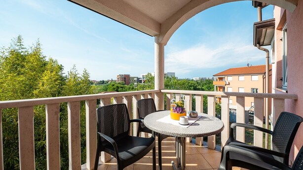 A balcony with two chairs and a small table, overlooking a cityscape. - A one bedroom apartment with balcony and private parking in town - Dragica 2 (Umag)
