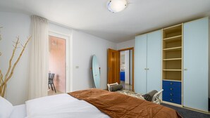 A hotel room with a bed, a wardrobe, a chair, and a surfboard. - A one bedroom apartment with balcony and private parking in town - Dragica 2 (Umag)