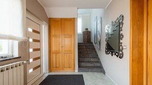 A hallway with a wooden door, a radiator, a black mat, and a staircase leading to another room. - A one bedroom apartment with balcony and private parking in town - Dragica 2 (Umag)