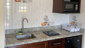 A kitchen with a granite countertop, a sink, a microwave, and wooden cabinets.