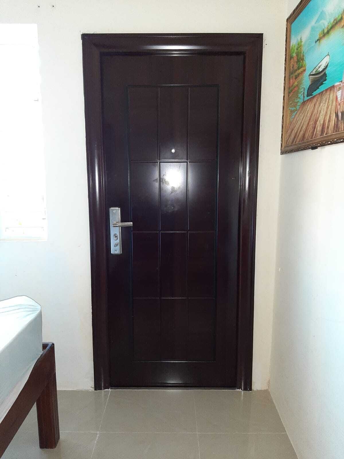 Une porte en bois sombre, dotée d’une poignée argentée et d’une petite fenêtre située juste au-dessus.