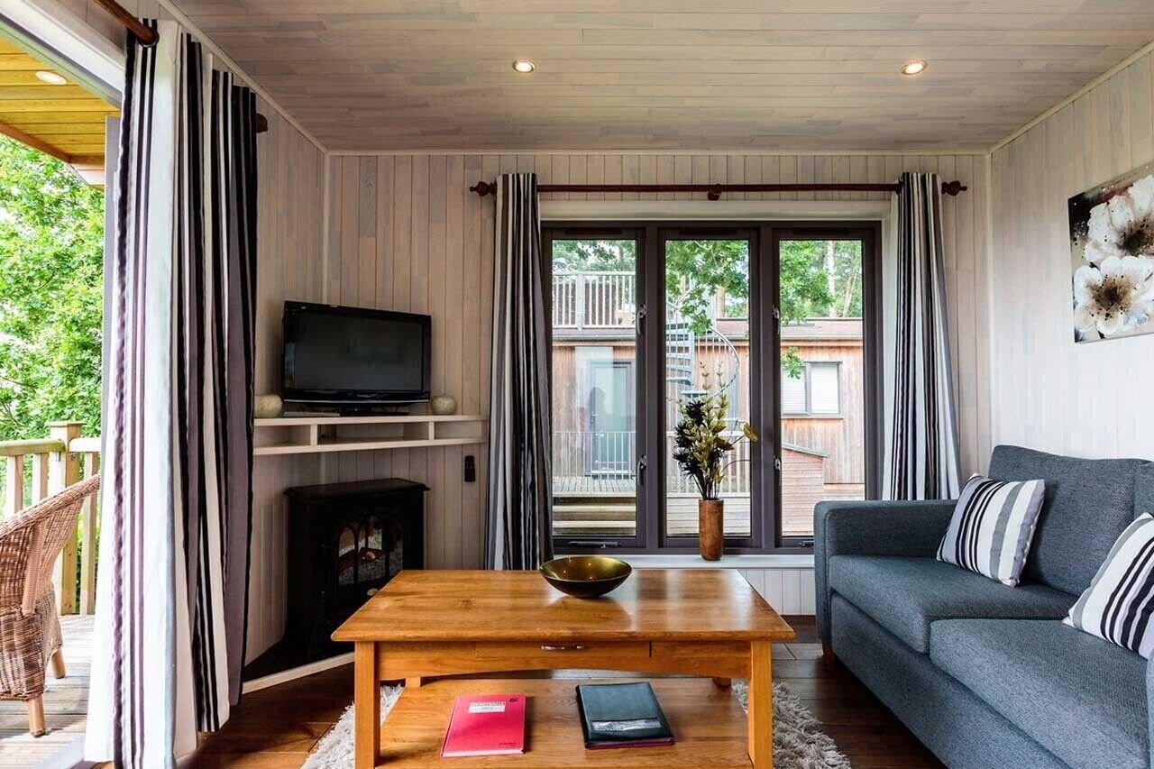 A cozy living room with a fireplace, a sofa, a coffee table, and a TV.