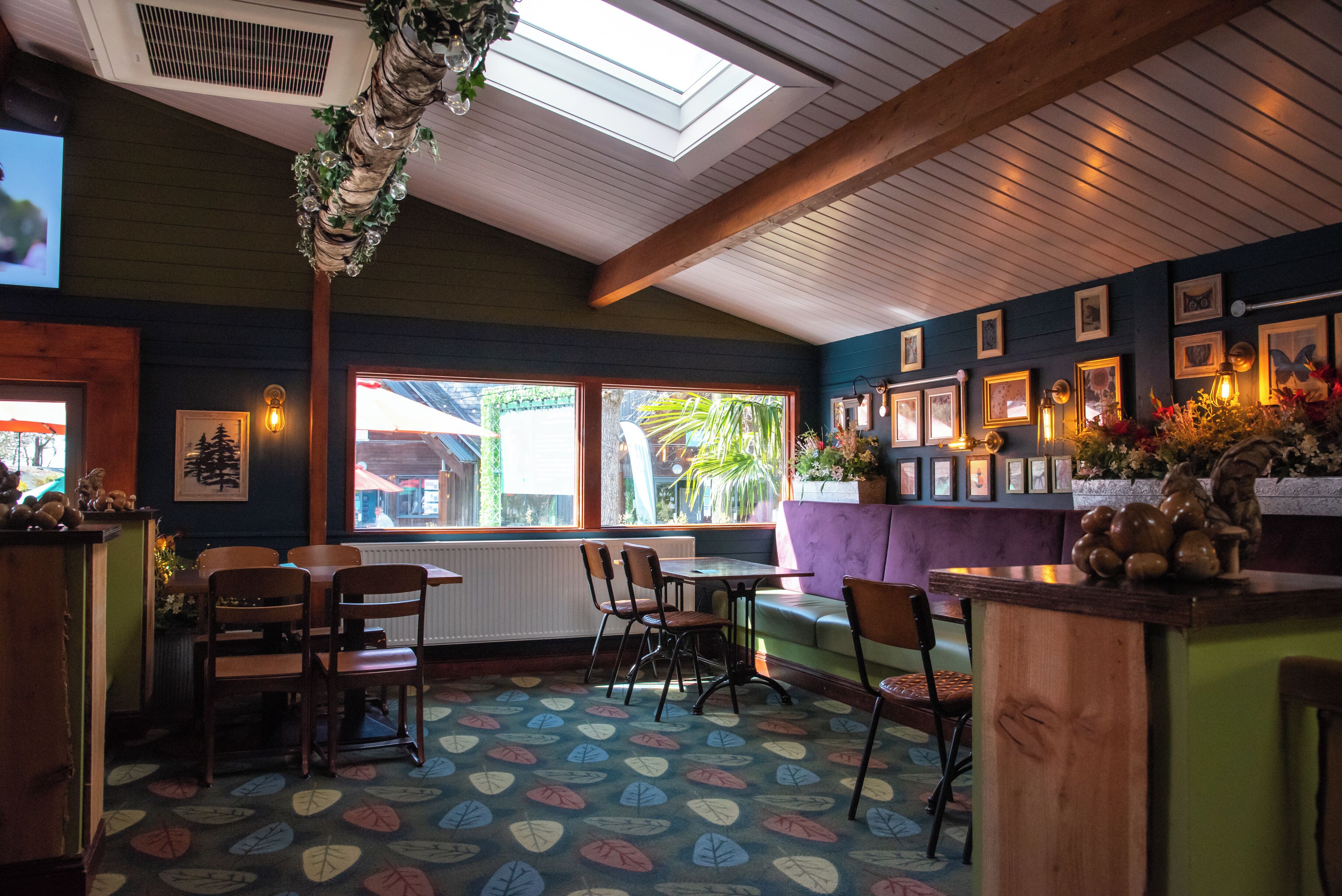 Un restaurant à l’ambiance chaleureuse, avec des meubles en bois, un sol à motifs et une vue sur l’extérieur.