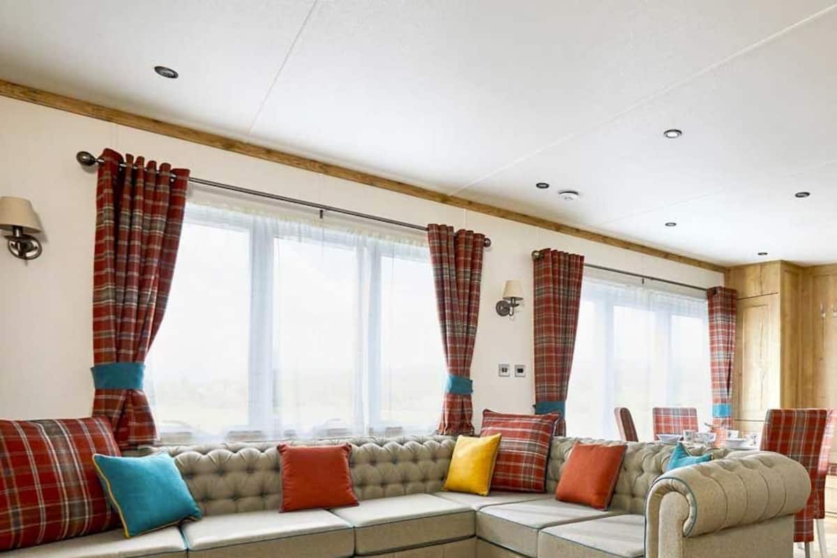 A modern living room with a sofa set, a flat-screen TV, and a kitchen area.