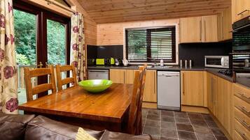 A wooden-paneled kitchen with a dining table, chairs, and a green bowl.