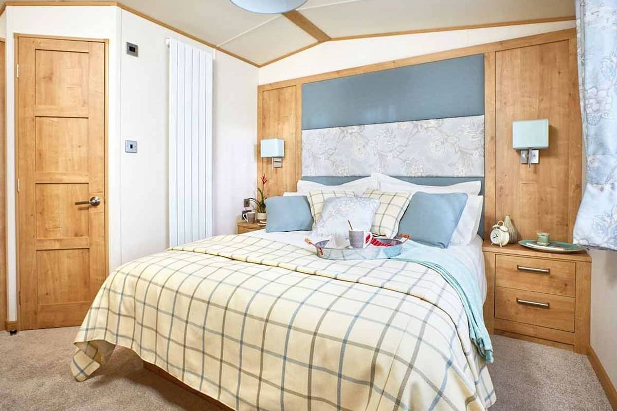 A bedroom with a large bed, a wooden headboard, bedside tables, and a nightstand.