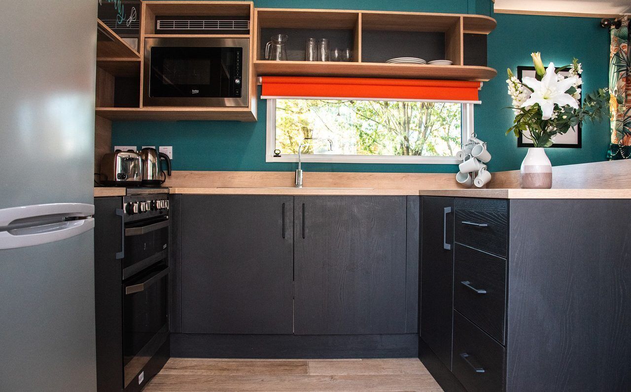 A modern kitchen with dark cabinetry, a microwave, and a sink.