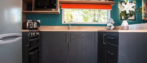 A modern kitchen with dark cabinetry, a microwave, and a sink.