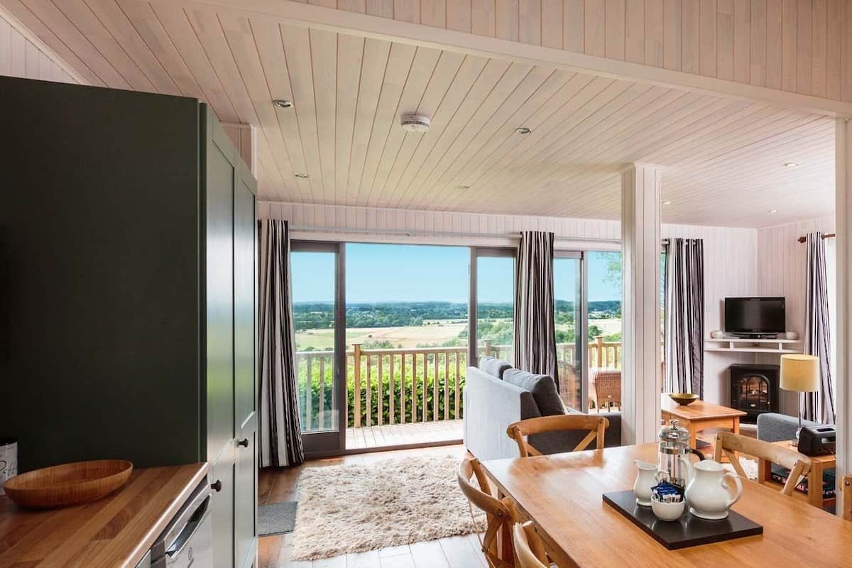 A spacious living area with a large window overlooking a scenic landscape, a dining area with a wooden table, and a cozy seating arrangement.