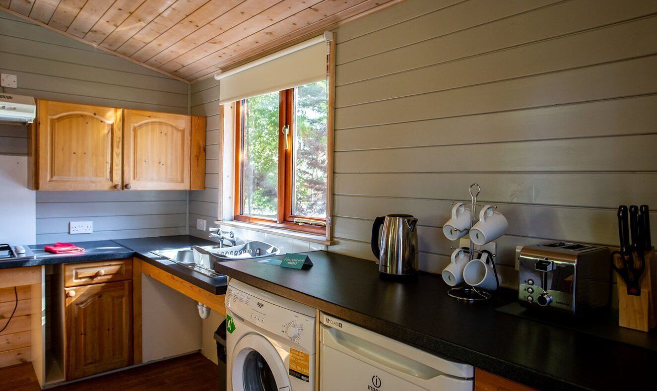 Una cocina compacta con armarios de madera, lavadora, tostadora y cafetera.