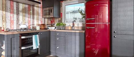 Une cuisine moderne avec un réfrigérateur rouge, un four encastré et des plans de travail en bois.
