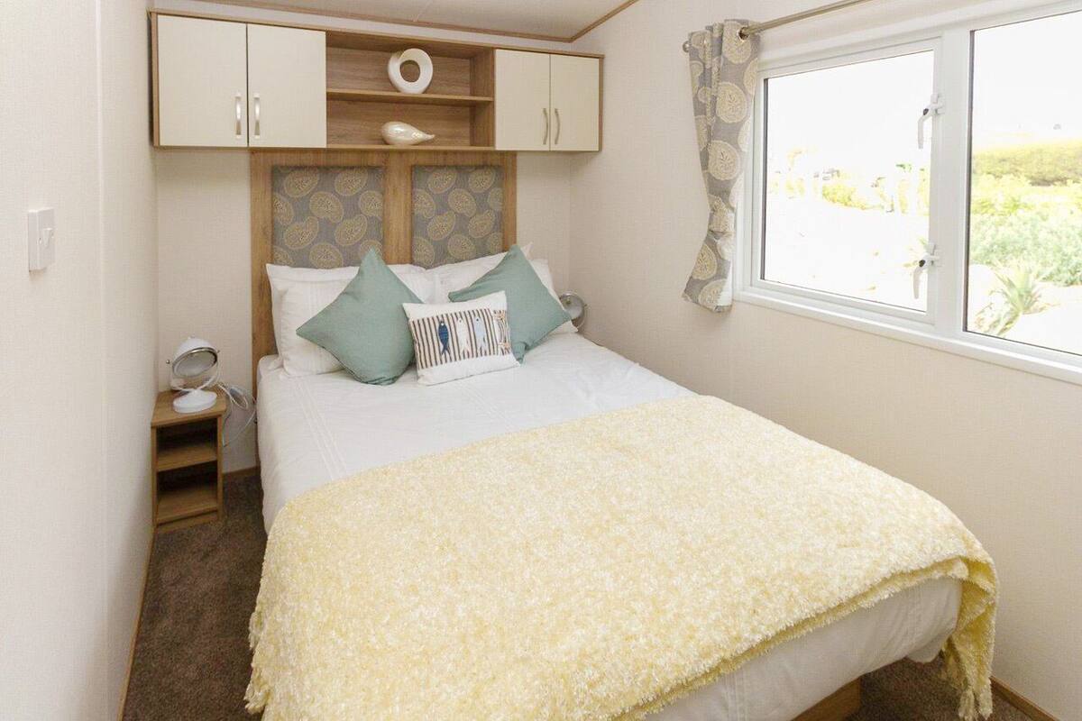 A bedroom with a bed, a bedside table, a wardrobe, and a window with a view.