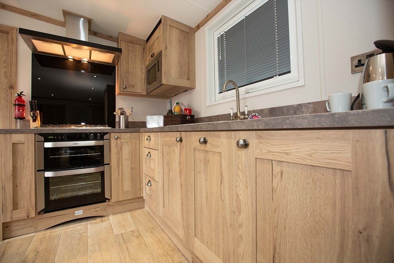 A kitchen with wooden cabinets, a built-in oven, and a window with blinds.