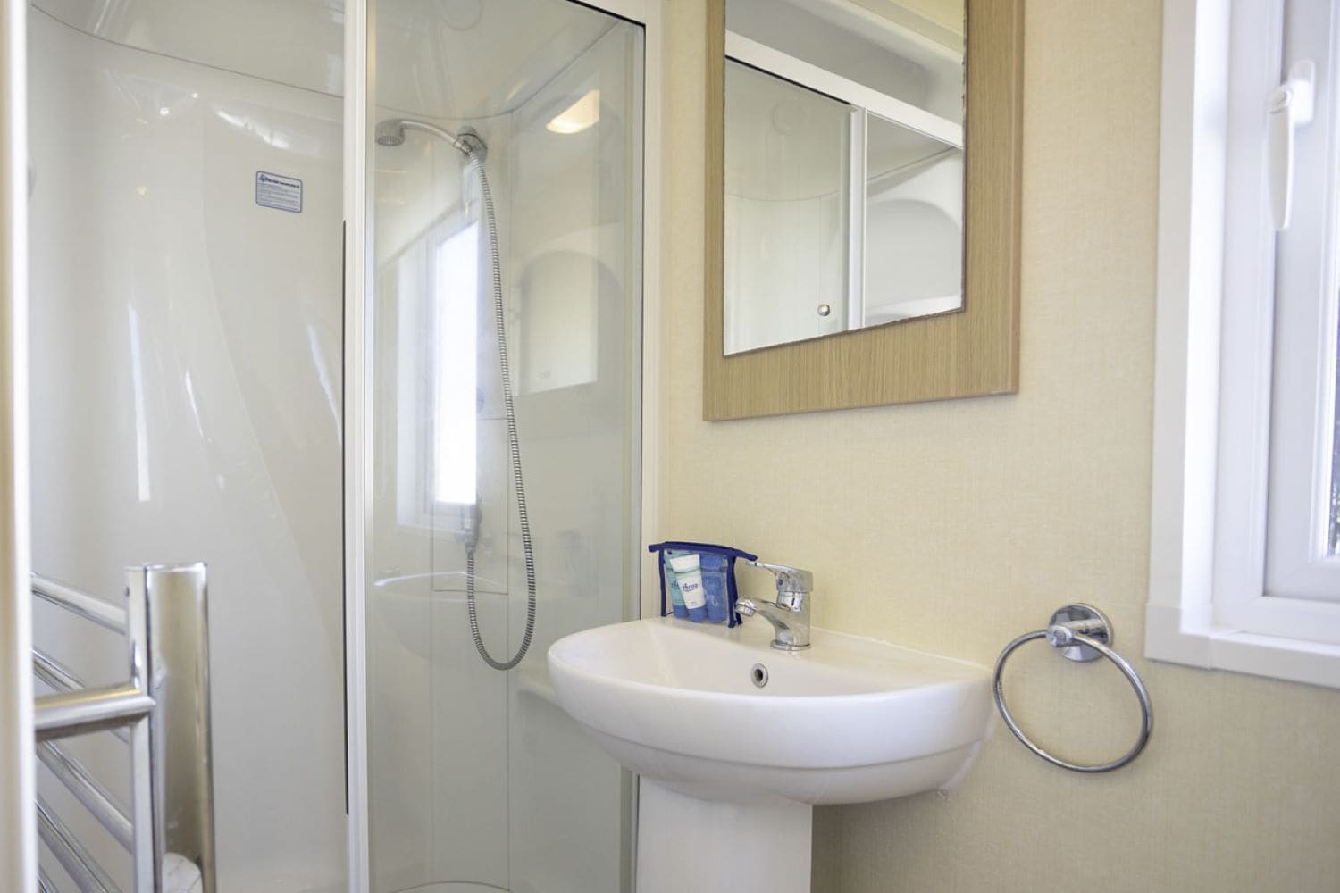 Une salle de bain avec une douche à parois de verre, un lavabo blanc et un miroir au-dessus.