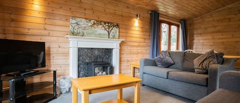 A cozy living room with a fireplace, a sofa, a TV, and a wooden table.