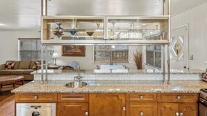 A kitchen with granite countertops, wooden cabinets, a stainless steel sink, and a built-in glass-fronted upper kitchen area. - Spectacular House on Lake Hamilton (Lake Hamilton)