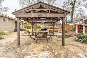 Relax in this serene outdoor space, featuring a pergola, table, and chairs, perfect for dining or socializing.