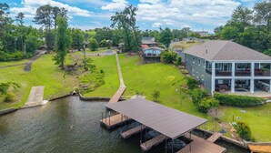 A residential area with a dock extending into a body of water, surrounded by houses and greenery. - Spectacular House on Lake Hamilton (Lake Hamilton)