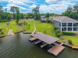 A residential area with a dock extending into a body of water, surrounded by houses and greenery.
