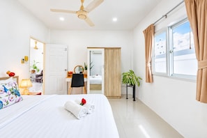 A hotel room with a bed, a desk, a chair, a ceiling fan, a window with curtains, and a plant. - Star villa 2 bedrooms /Private swimming pool for family (Tambon Chalong)