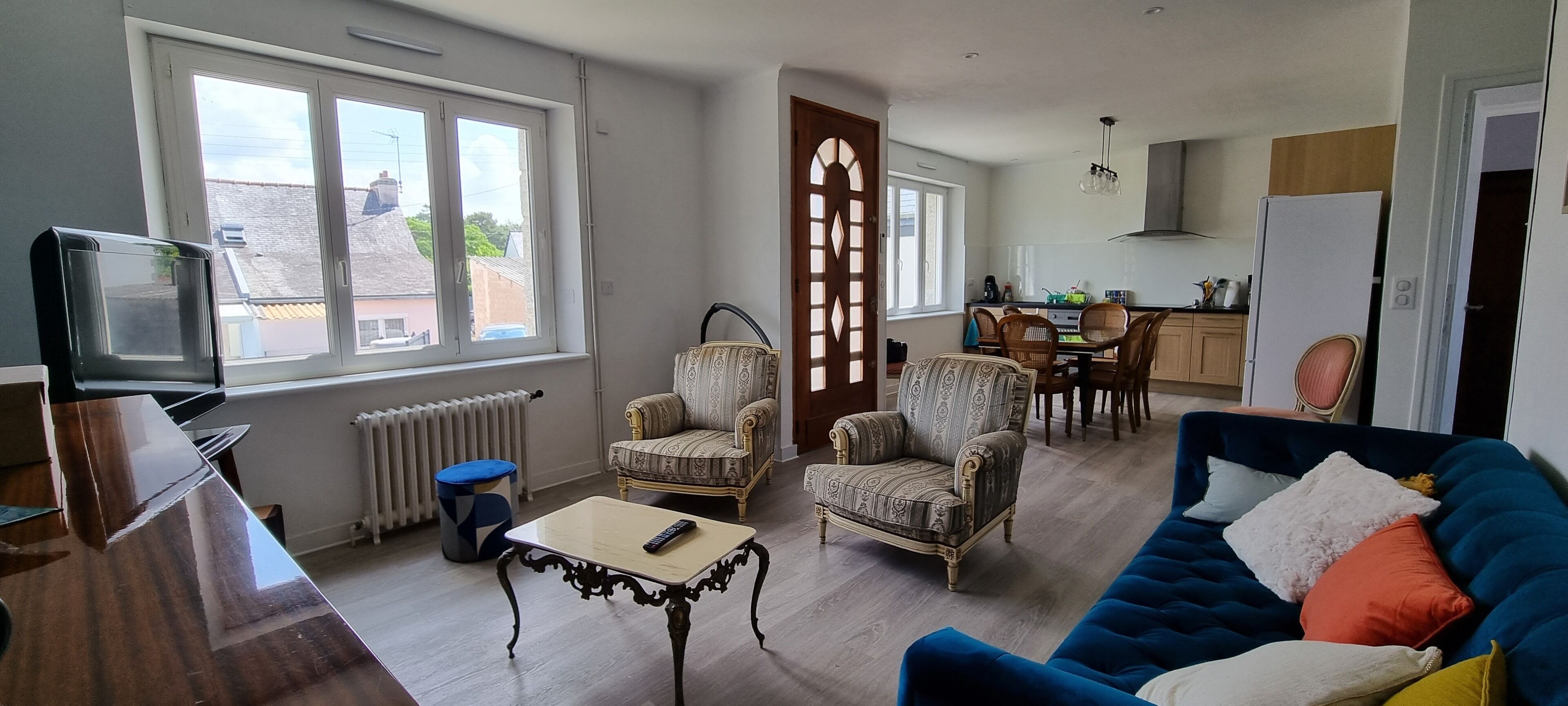 A living room with a blue sofa, patterned armchairs, a coffee table, and a TV.