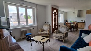 A living room with a blue sofa, patterned armchairs, a coffee table, and a TV. - Beautiful renovated house in Lambell - 5min from beaches and Tregunc center (Trégunc)