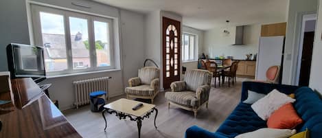 A living room with a blue sofa, patterned armchairs, a coffee table, and a TV.