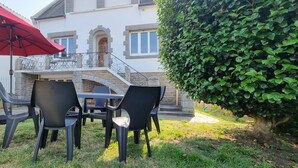 An outdoor patio with a table and chairs, a red umbrella, and a stone staircase leading to a balcony. - Beautiful renovated house in Lambell - 5min from beaches and Tregunc center (Trégunc)